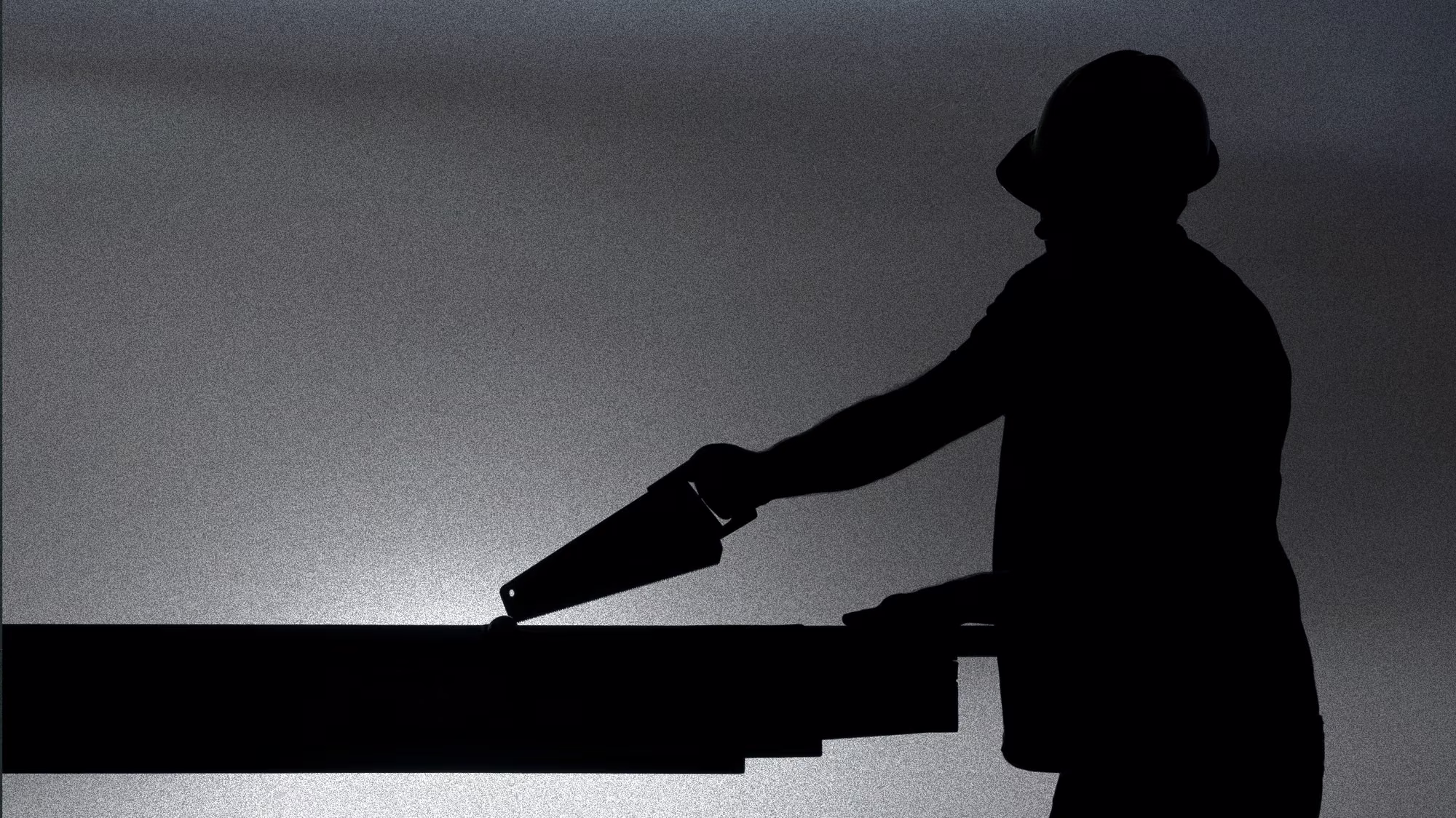 A carpenter cutting framing lumber at first light